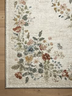 an area rug with flowers and leaves on the floor in front of a wooden floor