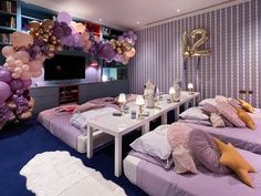 a room filled with lots of purple and gold balloons in the shape of animals sitting on top of twin beds