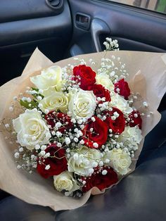 a bouquet of white and red roses in the back seat of a car