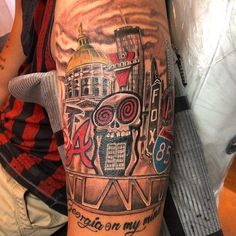 a man with a tattoo on his arm has a skull and cityscape in the background