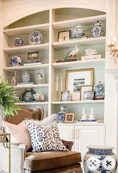 a living room filled with lots of furniture and shelves covered in blue and white vases