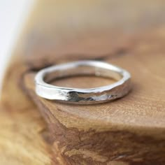 a silver ring sitting on top of a wooden table next to a piece of wood