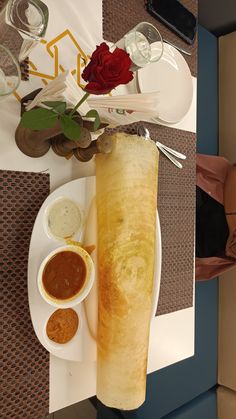 a long piece of bread sitting on top of a white plate next to some dipping sauces