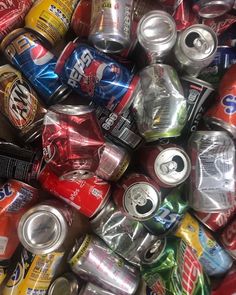 a pile of soda cans and cans stacked on top of each other in different colors