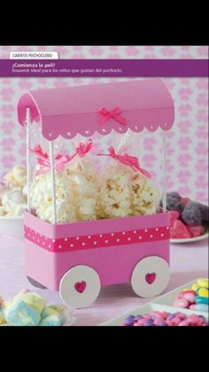 a pink wagon filled with popcorn and marshmallows on top of a table