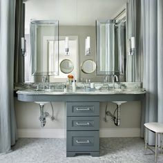 a bathroom with two sinks and mirrors in the middle, along with curtains on either side