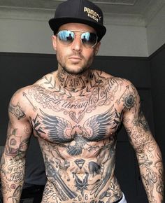 a shirtless man with tattoos on his chest wearing sunglasses and a baseball cap is looking at the camera