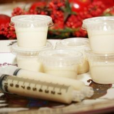 several plastic containers filled with white liquid next to a syringe