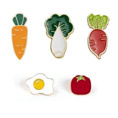 four enamel pins with vegetables and an egg on top, one in the shape of a heart