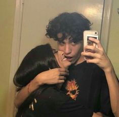 two people hugging each other while taking a selfie in the mirror with their cell phone