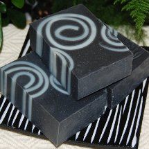 three bars of soap sitting next to each other on top of a black and white striped table cloth