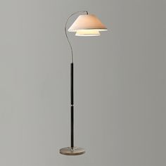 a floor lamp with a white shade on it and a black pole in the middle