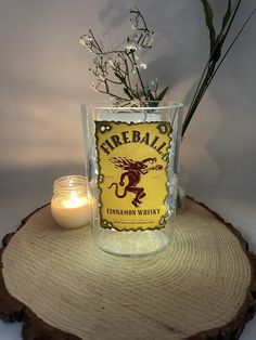 there is a candle and some flowers on top of a tree stump with a sign that says pipeball cinnamon whiskey