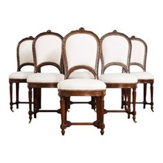 six chairs with white upholstered seats and wood trimmings on the back