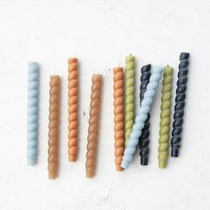 four different colored toothbrushes lined up on a white surface, with one in the middle