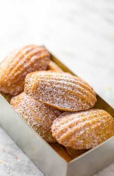 powdered sugar covered doughnuts in a metal box on a white tablecloth