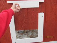 a person is holding the door to a red wall with a white frame on it