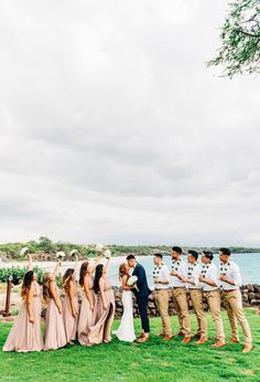 a group of people standing on top of a lush green field next to the ocean