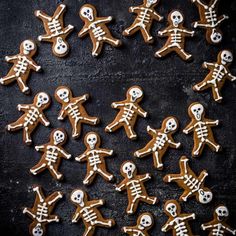 ginger cookies decorated with icing in the shape of skeletons on a black background, top view