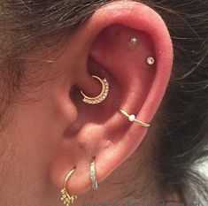 a woman wearing three different types of ear piercings