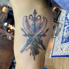 a tattoo on the leg of a man with two crossed swords and a key in it