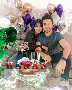 a man and woman sitting on a couch in front of a birthday cake