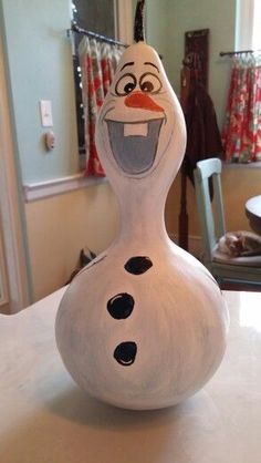 a snowman shaped vase sitting on top of a table next to a chair and mirror