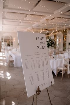 a white sign sitting on top of a table in a room filled with tables and chairs