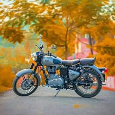 the motorcycle is parked on the side of the road in front of some colorful trees