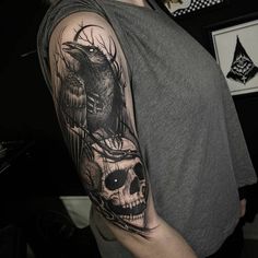 a man with a black and grey tattoo on his arm holding a bird in front of him