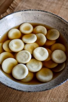 a white bowl filled with sliced bananas on top of a brown cloth covered tablecloth