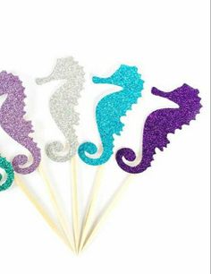 four seahorses on sticks with glitter in the shape of them, one is purple and one is green