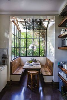 a kitchen with a table and benches in front of a window that looks out onto the garden