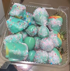 a plastic container filled with blue and green desserts on top of a countertop