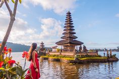 a woman standing in front of a body of water with pagodas on the other side