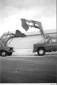 two trucks parked in front of a building with a crane on it's back