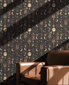 a chair sitting in front of a wall covered with flowers and moon phases on it