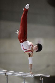 a young man doing a handstand on the balance beam