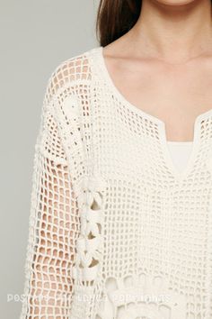 a woman wearing a white top with crochet details on it's sleeves