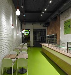 an empty restaurant with green flooring and white brick walls