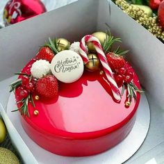 a heart shaped cake with strawberries and candy canes on top in a box