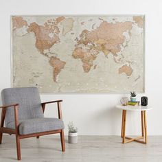 a chair sitting in front of a large map on the wall next to a table