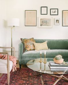 a living room with green couches and pictures on the wall above it's coffee table