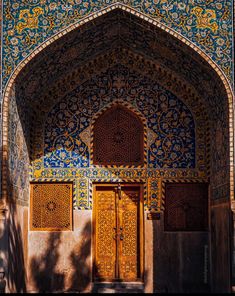 the entrance to an ornate building with blue and yellow tiles on it's walls