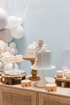 a table topped with cakes and cupcakes on top of wooden crates next to balloons