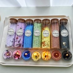 an assortment of different colored donuts on a white platter with candles in them