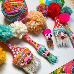 several colorful hairbrushes decorated with pom - poms on top of a table