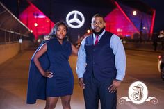 a man and woman standing next to each other in front of a mercedes dealership