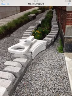 a stone bench sitting in the middle of a gravel path next to a brick building