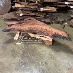 a wooden bench made out of wood sitting on top of a floor next to stacks of lumber